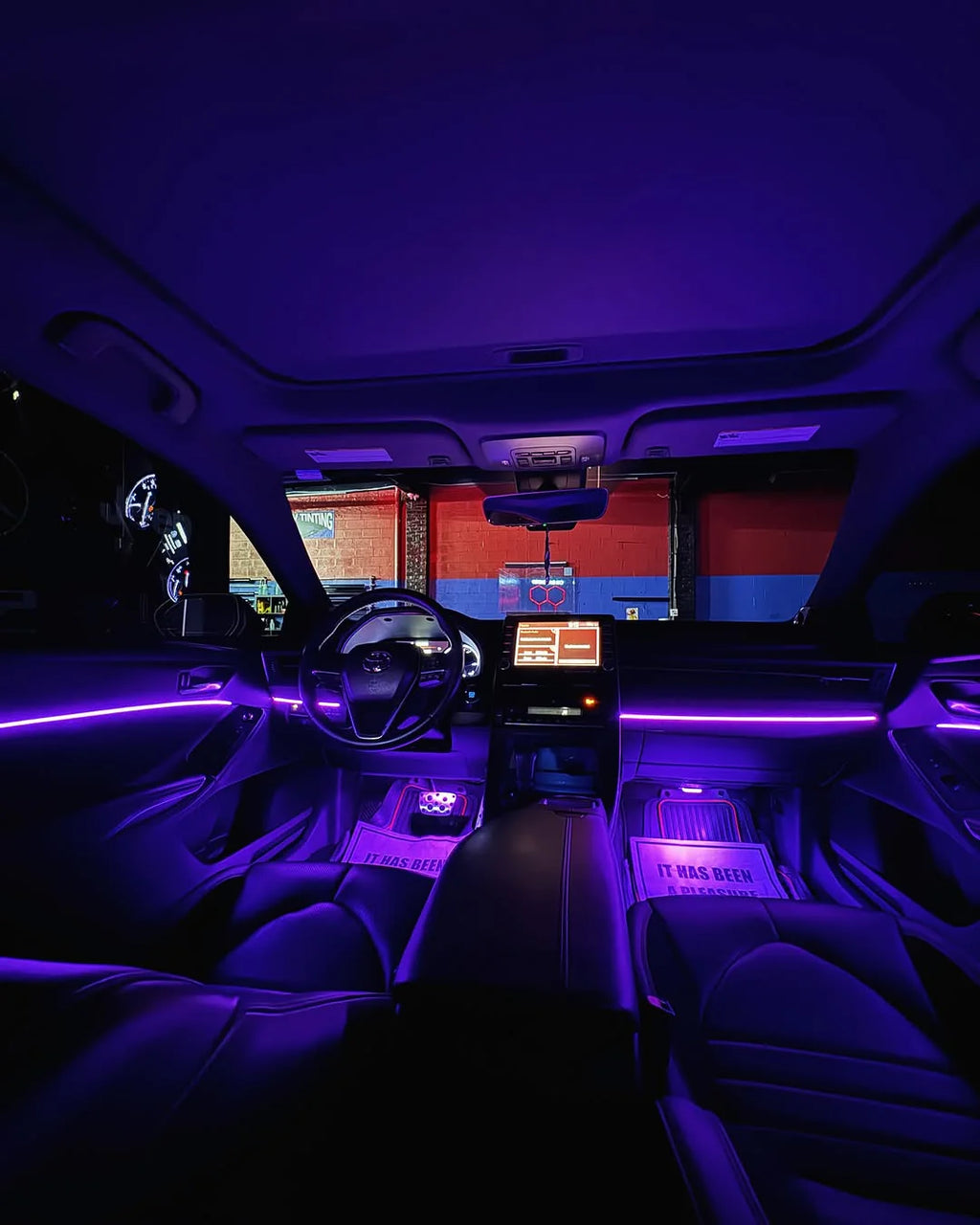 Car interior at night with purple RGB ambient lighting on dashboard and footwells – Midnight Auto light kit
