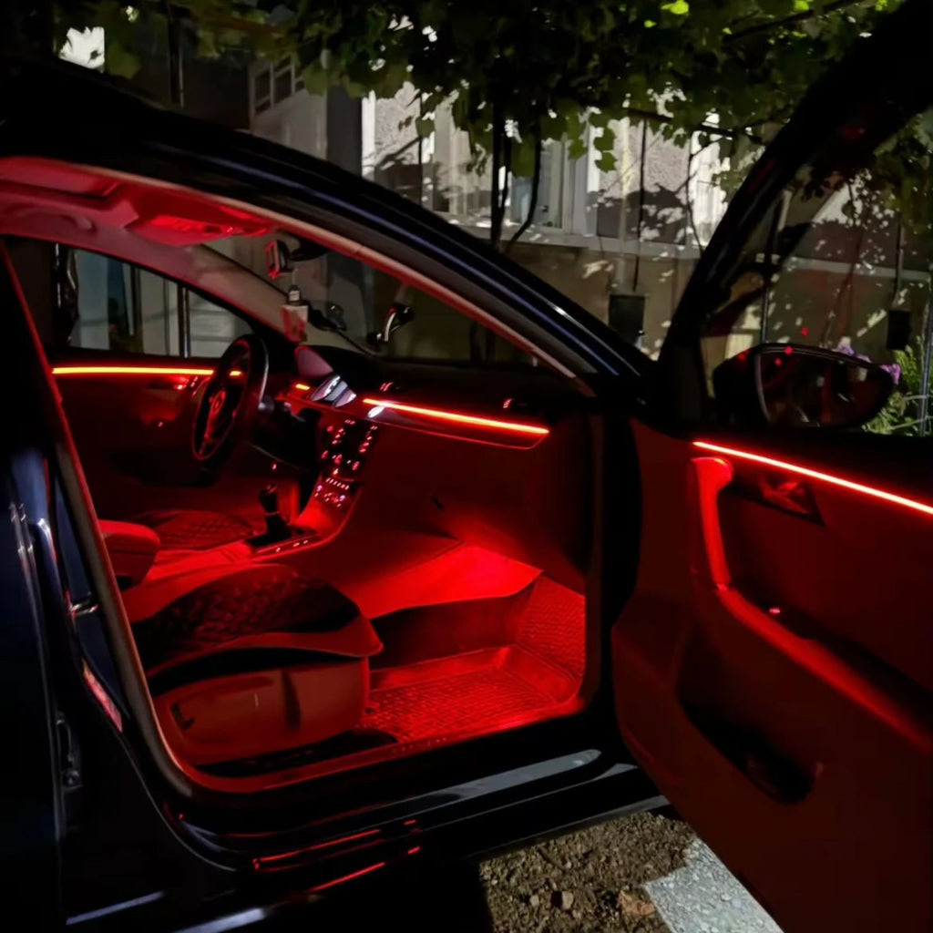 Car interior glowing with red RGB ambient lighting along the door and footwell at night